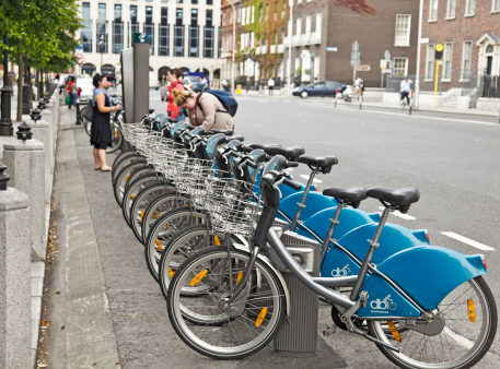 爱尔兰共和国都柏林--2011年7月14日：位于都柏林市中心圣斯蒂芬绿地的Dublinbikes站点，一些人正在租借自行车，并查看付费站点的情况。Dublinbikes是一个公共自行车租赁系统，在市中心有44个站点和550辆自行车。他们自2009年以来一直在运营。