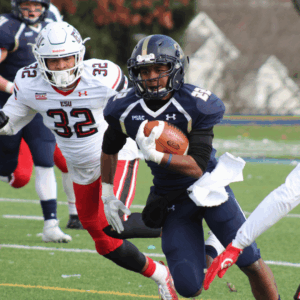NFL Weekend in Dublin: A football player in a navy blue uniform is running with the ball, pursued by players in white and red uniforms on a green field. The background shows blurred trees and buildings.