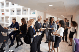 Professionals networking at an Air Finance Dublin event in a bright, modern venue, engaging in conversations over food and drinks, dressed in business attire with name badges.