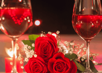 The Grafton Hotel Romantic hotel setting in Dublin with two glasses of red wine, red roses, and candlelight on an elegant table.